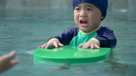 Madre-enseñando-niño-nadar-en-una-piscina.-El-niño-está-asustado-y-caminando-en-el-agua-a-mamá.