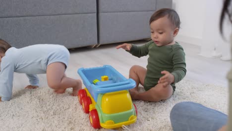 Mellizos-asiáticos-luchando-por-un-gran-coche-de-juguete-en-casa