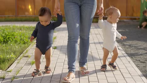 Unrecognizable-Woman-Walking-with-Toddlers-in-Garden