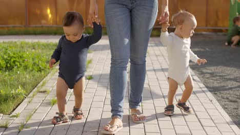 Mujer-irreconocible-caminando-con-niños-pequeños-en-el-jardín