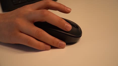 Young-female-hand-using-black-computer-mouse-on-white-table