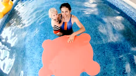 Schwimmbad.-Mama-bringt-einem-kleinen-Kind-das-Schwimmen-im-Pool-bei.