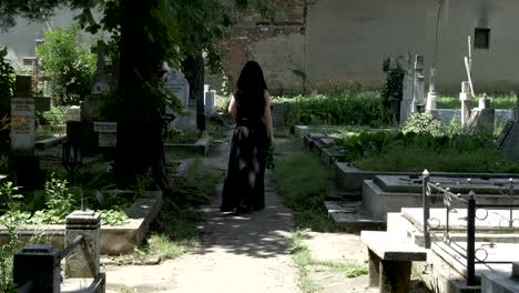 Creepy-woman-walking-in-cemetery-alley-to-beloved-grave-and-placing-a-crown-on-grave