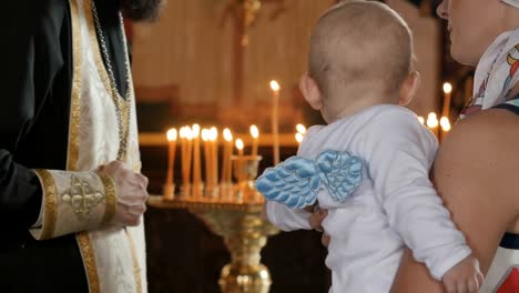 Mutter-hält-einen-kleiner-Junge-in-Armen-und-hört-einen-Priester-in-der-Kirche