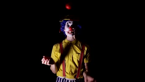 A-clown-juggles-red-apples-and-shows-his-teeth.