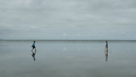 "Out"!-Zwei-Jungen-spielen-Beach-Cricket,-trifft-der-Werfer-das-Wicket!