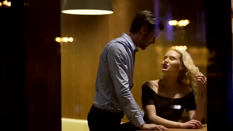 Man-flirting-with-gorgeous-blond-woman-at-restaurant-in-the-evening,-pick--up