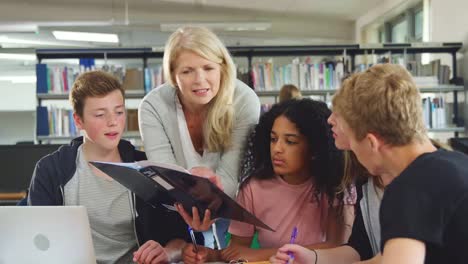 Weibliche-Lehrer-arbeiten-mit-College-Studenten-In-der-Bibliothek