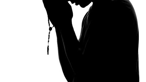 Religious-person-praying,-male-silhouette-holding-rosary-in-hand,-hope-and-faith
