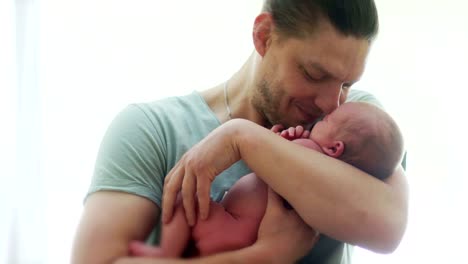 A-mature-father-cradle-his-month-old-baby-in-the-arms.-The-man-laughs-happily.-Father's-Day.-Children's-Day