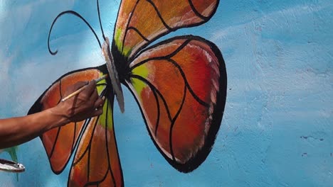 Wandmaler-malt-Schmetterling-in-Farbe-auf-die-Wand-der-Schule.