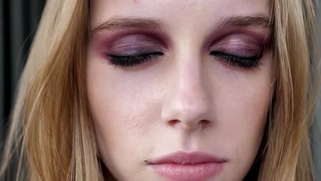 Young-pretty-women-with-heavy-make-up-slowly-opening-eyes-and-looking-in-camera,-portrait,-striped-wall-background