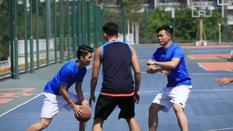 adultos-jóvenes-asiáticos-jugando-baloncesto-en-la-cancha-al-aire-libre