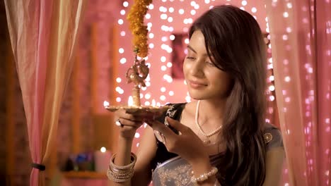 Slow-motion-shot-of-a-happy-female-in-a-traditional-clothing-lighting-a-hanging-metal-lamp-in-a-house-decorated-with-lights-and-flowers