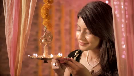 A-close-up-of-Indian-traditional-woman-lighting-a-lamp-during-Diwali-festival.