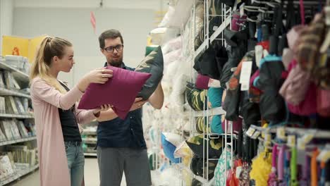 Joven-casado-pareja-se-disputa-en-una-tienda,-elegir-almohadas-decorativas