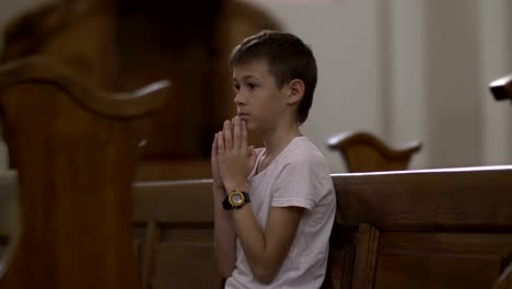 serious-boy-praying-in-the-Church-alone,-back-view