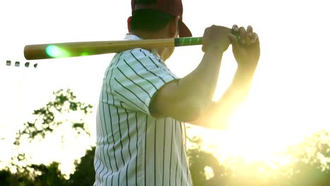 Práctica-de-béisbol-de-los-hombres-golpeando-una-pelota-de-béisbol-con-la-luz-del-atardecer