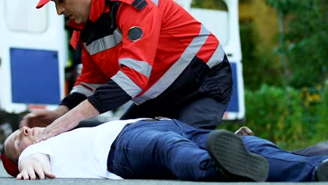 Paramedic-crew-running-to-man-lying-on-road,-first-aid-after-accident,-ambulance
