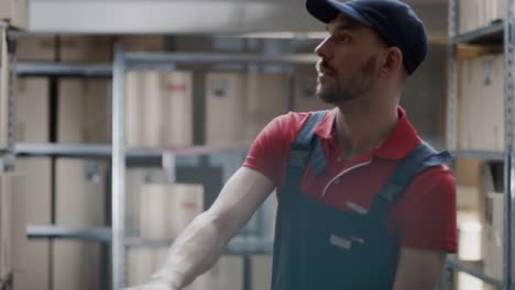 Warehouse-Worker-Collects-Order-by-Taking-Cardboard-Boxes-and-Parcels-of-the-Shelf-and-Putting-them-On-a-Trolley.