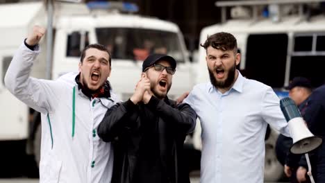 Angry-football-fans-scream-on-street-in-a-megaphone.-Caucasian-people-on-strike.