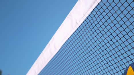 Zeitlupe:-Gelbe-und-blaue-Kugel-fliegt-ins-Netz,-während-ein-Volleyball-Spiel.