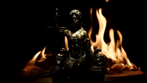 Statue-der-Justitia-auf-dem-Hintergrund-der-Flamme-eines-brennenden-Buches