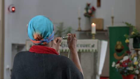 A-black-woman-kneeling-and-holding-rosary-beads.