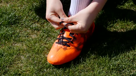 Football,-soccer-game.-Professional-footballer-young-woman-buckle-her-red-shoes-before-training,-4k