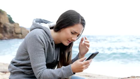 Trauriges-Mädchen-erhält-schlechte-Nachrichten-online-am-Strand