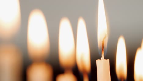 Detail-shot-of-the-flames-on-a-group-of-white-candles,-burning-for-the-Jewish-holiday-of-Hanukkah,-which-are-blown-out,-selective-focus