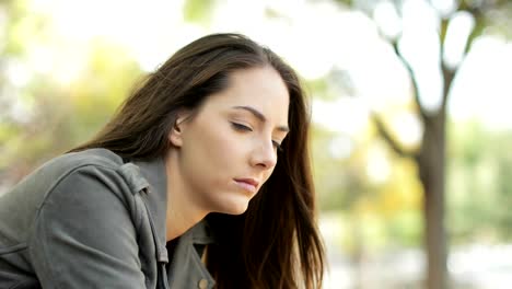 Sad-pensive-woman-sitting-in-a-park