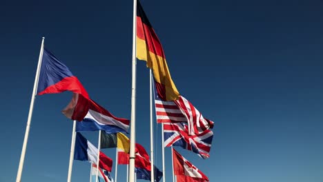National-flags-together-flying-in-slow-motion-on-blue-sky-background