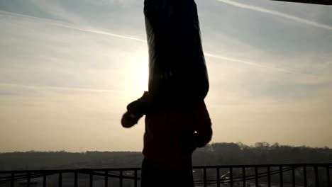 Ein-Mann-Schläge-hart-in-Tasche-auf-Boxtraining,-Silhouette-der-Boxer,-Sonne,-Sportler-üben,-Krafttraining,-starker-Kerl-hart-trainieren,-Kraft-Übungen,-Training,-handheld,-sonnigen-Tag.