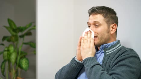 Handsome-unshaved-man-blowing-nose-to-napkin.