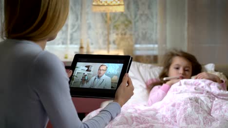 Mom-with-a-little-sick-daughter-gets-a-doctor's-consultation-using-video-chat-at-home.