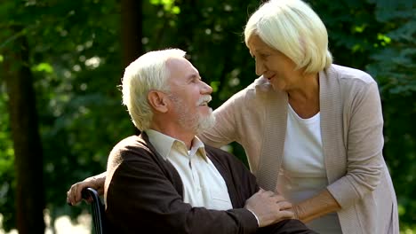 Old-handicapped-man-hugging-and-kissing-his-beautiful-wife,-pastime-together