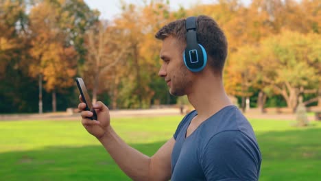 handsome-man-with-earphones-walks-outdoors