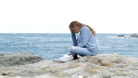 Adolescente-triste-sentado-en-la-playa-en-un-día-ventoso