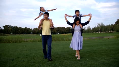 Cheerful-asian-parents-carrying-kids-on-shoulders