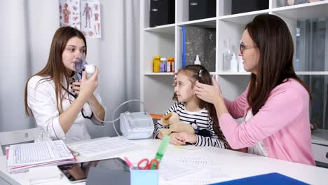 Madre-apoya-y-calma-a-pequeña-hija-en-el-consultorio-médico-hasta-su-ingaliruut-hija-usando-un-nebulizador-máscara.