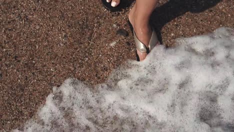 Woman's-feet-in-sandals-on-beach.