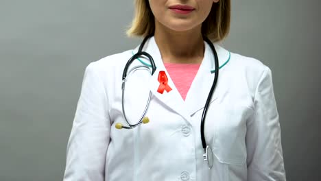 Woman-physician-with-red-ribbon-posing-for-camera,-AIDS-awareness,-sti-disease