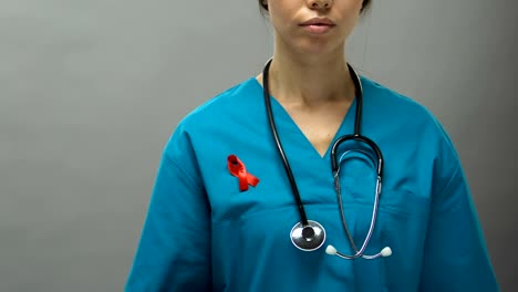 Médico-mujer-seria-con-cinta-roja-apoyando-la-campaña-de-sensibilización-contra-el-SIDA