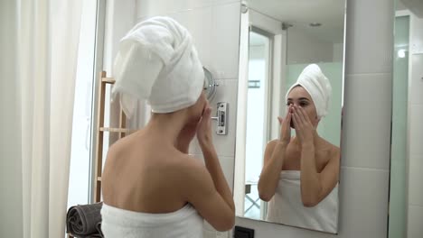 Cuidado-de-la-piel-del-rostro.-Mujer-aplicación-de-crema-sobre-la-piel-en-el-baño