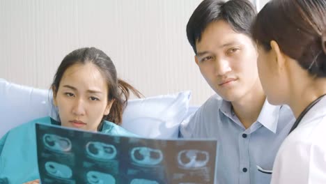 Doctor-showing-X-ray-scan-results-to-pregnant-woman-and-her-husband-with-serious-emotion.-People-with-healthcare-and-medical-concept.