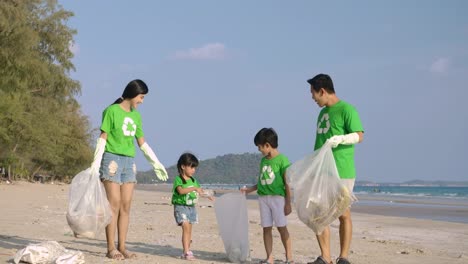 Group-of-volunteers-in-green-t-shirts-cleaning-up-the-beach-with-plastic-bags-full-of-garbage.-Slow-Motion.-Safe-ecology-concept.-4k-resolution.