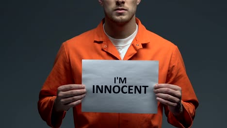 Im-innocent-phrase-on-card-in-hands-of-Caucasian-prisoner,-criminal-injustice