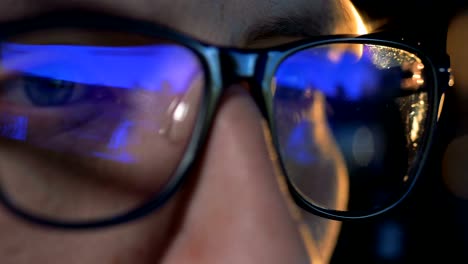 Close-up-of-glasses-put-on-a-man-with-a-computer-game-reflecting-in-them