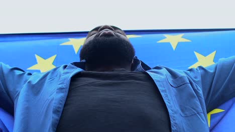 Hombre-negro-que-levanta-la-bandera-de-la-Unión-Europea,-confiado-en-la-supremacía-del-Derecho-de-la-UE